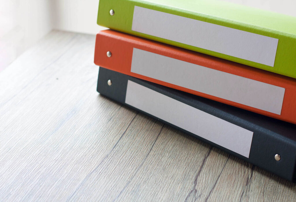 A navy, orange, and green notebook stacked on table