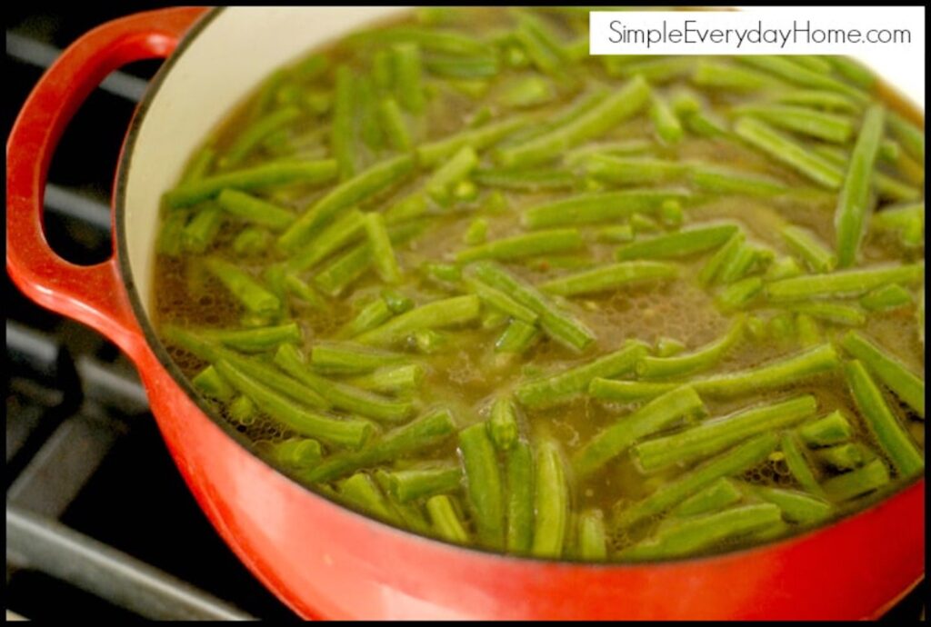 Green beans with broth cooking in a Dutch oven