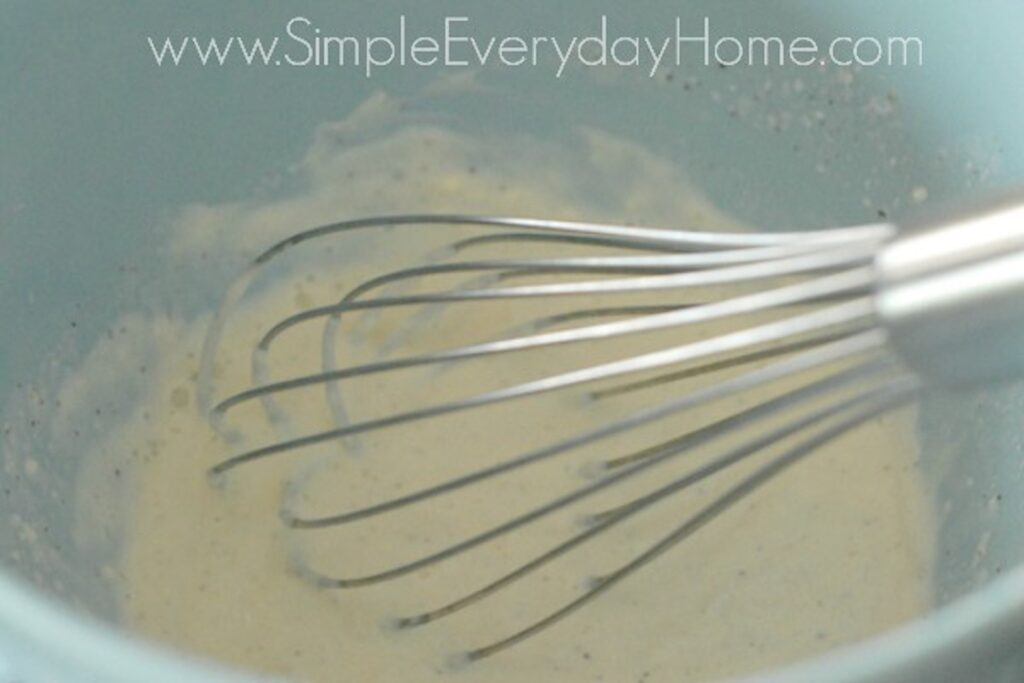 Mayo and milk being whisked in blue bowl