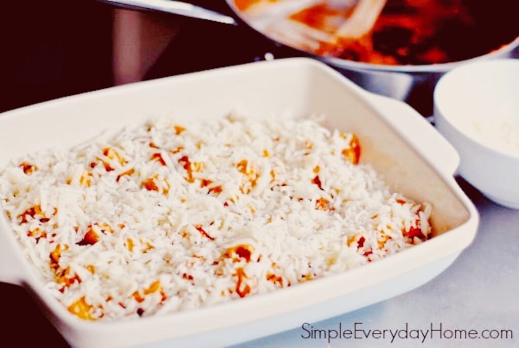 Rigatoni with cheese sprinkled on top in baking dish