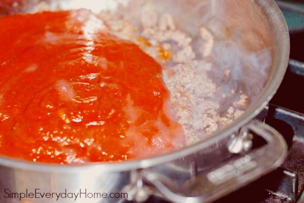 Sauce poured on top of ground beef in pan