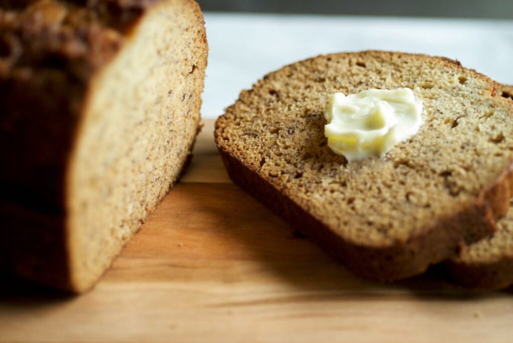 Sliced banana bread with butter on wooden board