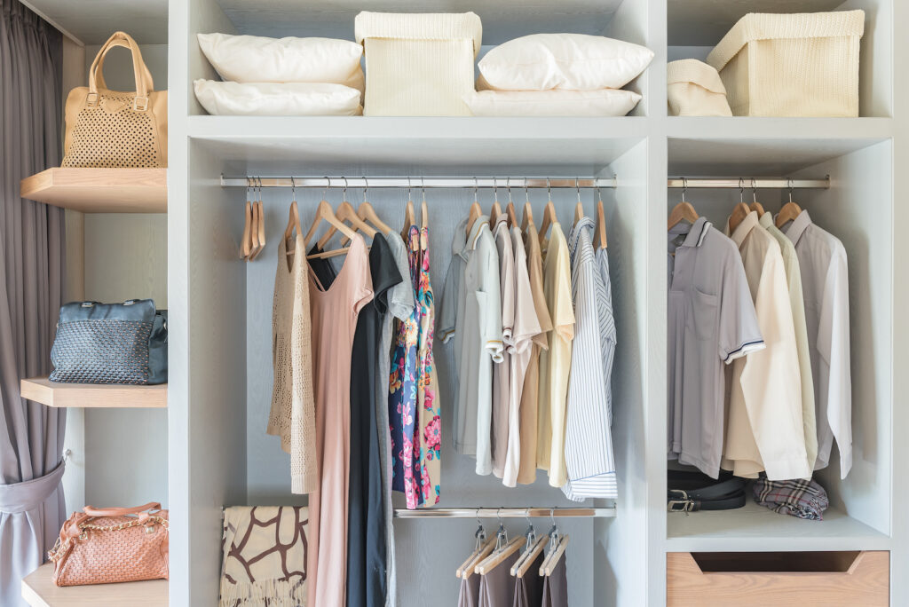 an organized closet with clothes and pillows on the shelves