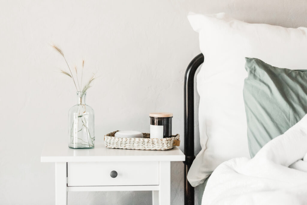 A bed with a green pillow and a bedside table