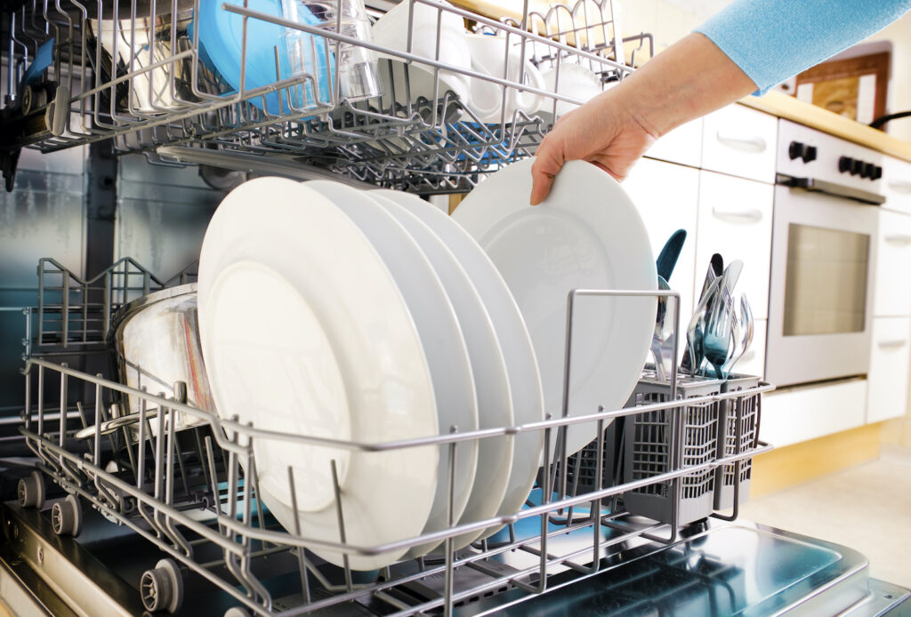 a woman's hand putting dishes in the dishwasher