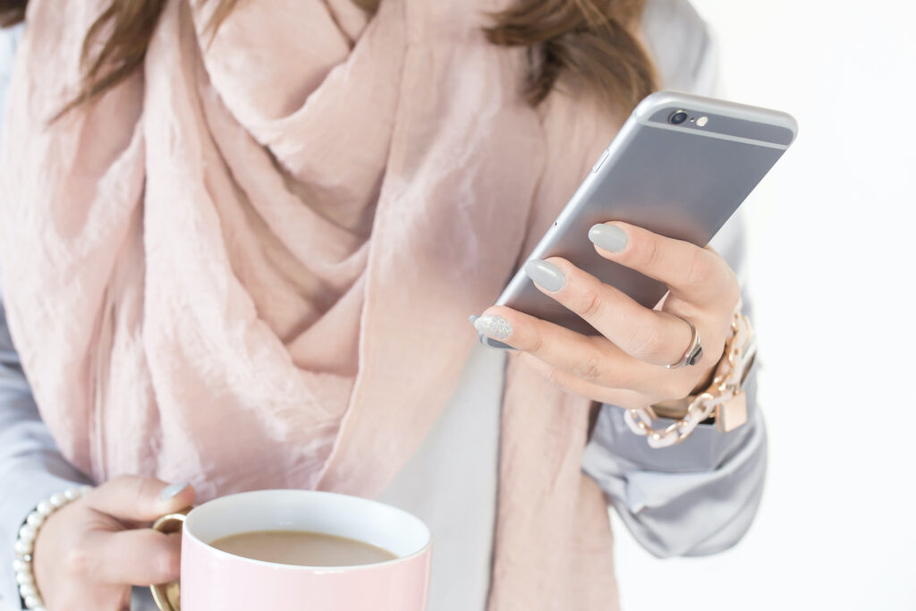 A woman holding a cup of coffee and looking at her phone