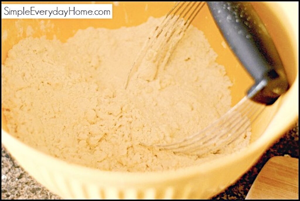 Pastry cutter setting in flour mixture in yellow bowl