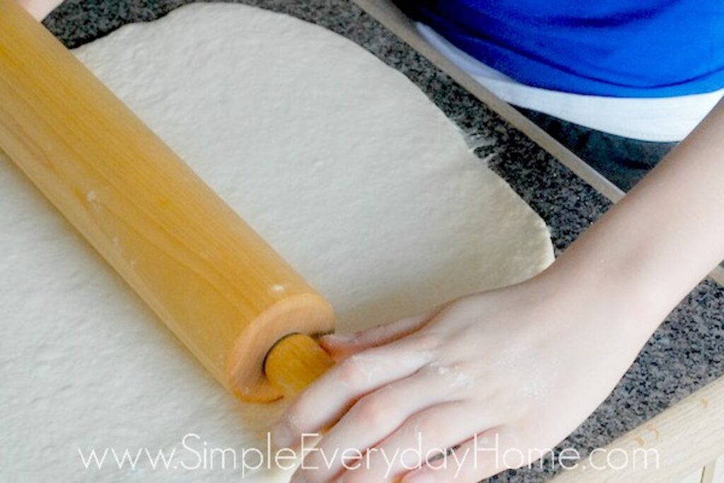 Bread dough being rolled with rolling pin