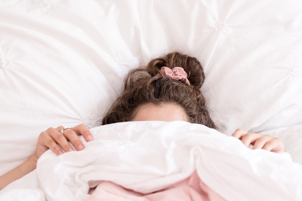 a woman with the bed covers pulled up over her head