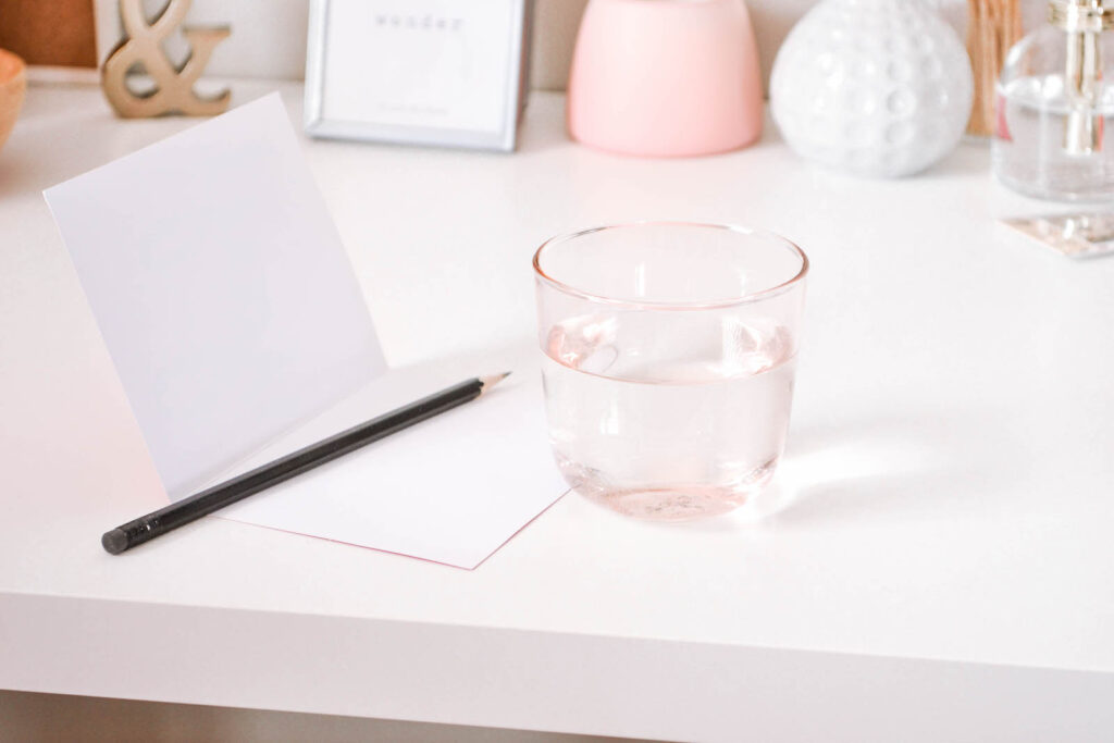 A glass of water beside a pencil and paper