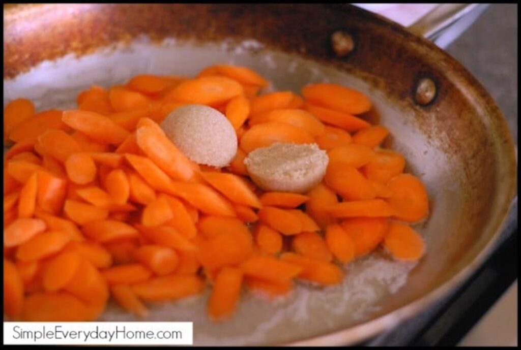 Carrots in pan with two spoons of brown sugar