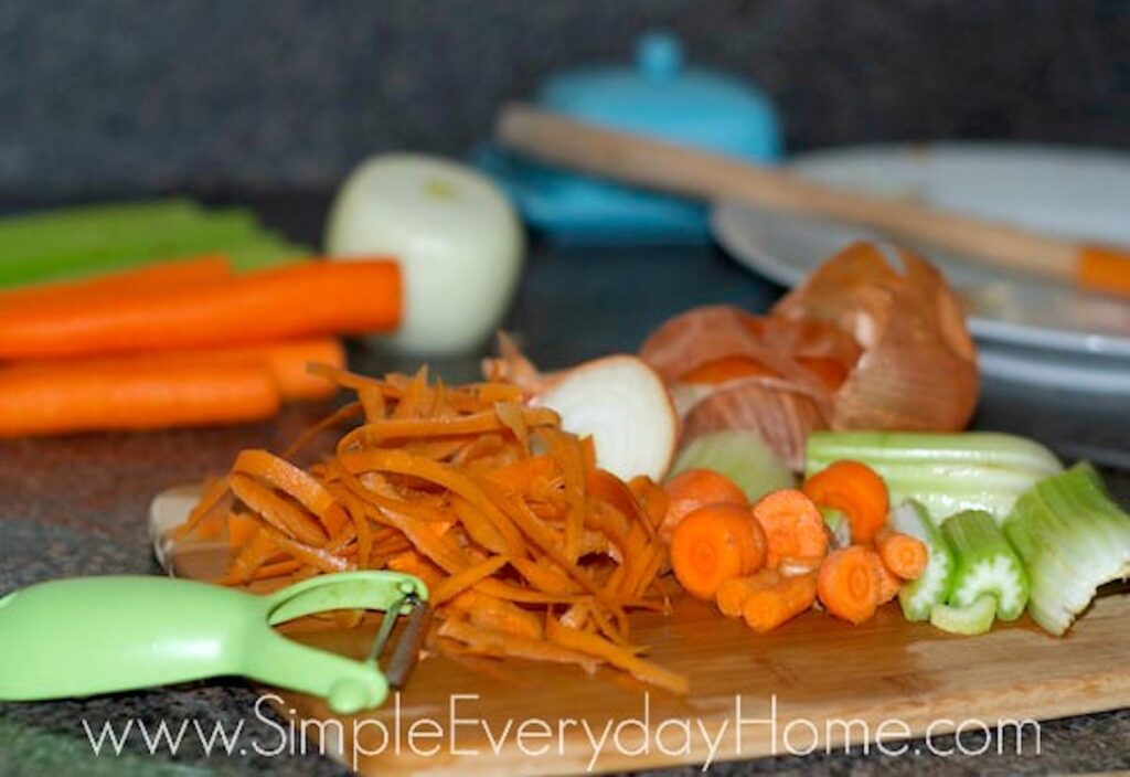 Carrots, carrot peels, celery, and onion peels on cutting board