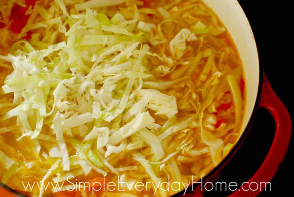 Soup in Dutch oven with sliced cabbage in it